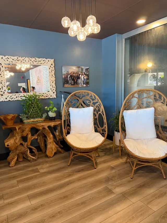 Two rattan peacock chairs with white cushions under a globe-bulb chandelier in the Tranquility Spa lounge